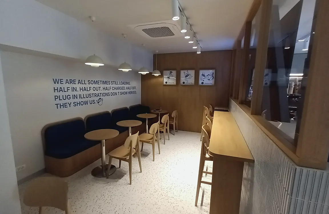 Zonă de lounge într-o cafenea, cu banchete și mese din lemn